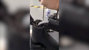 Zwei Hände, die die Lenkstange am Shift iQ E-Scooter mit Spezialwerkzeug anpassen.