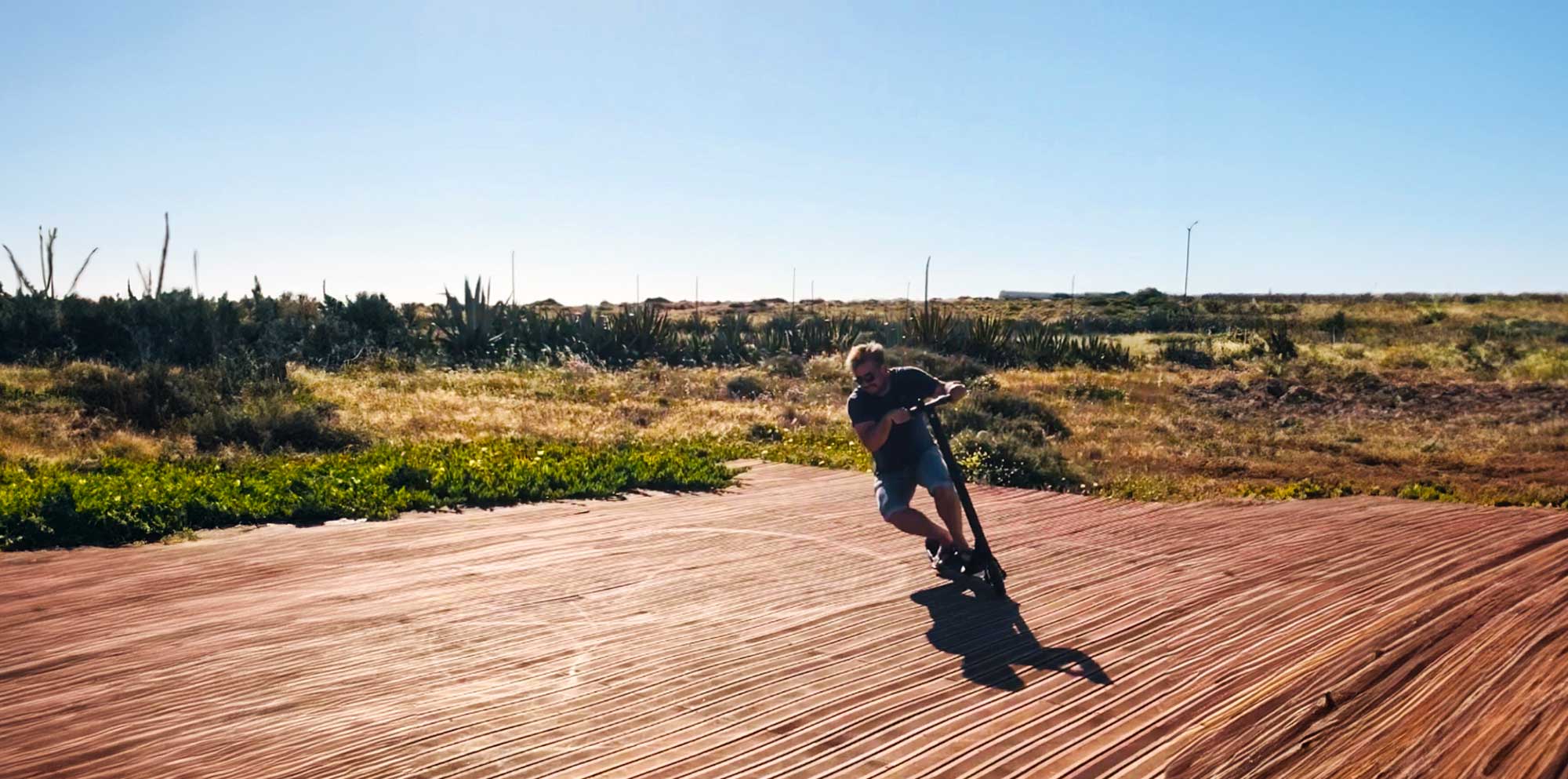 Ein Mann der auf einem Shift iQ E-Scooter in einer kargen Landschaft fährt.