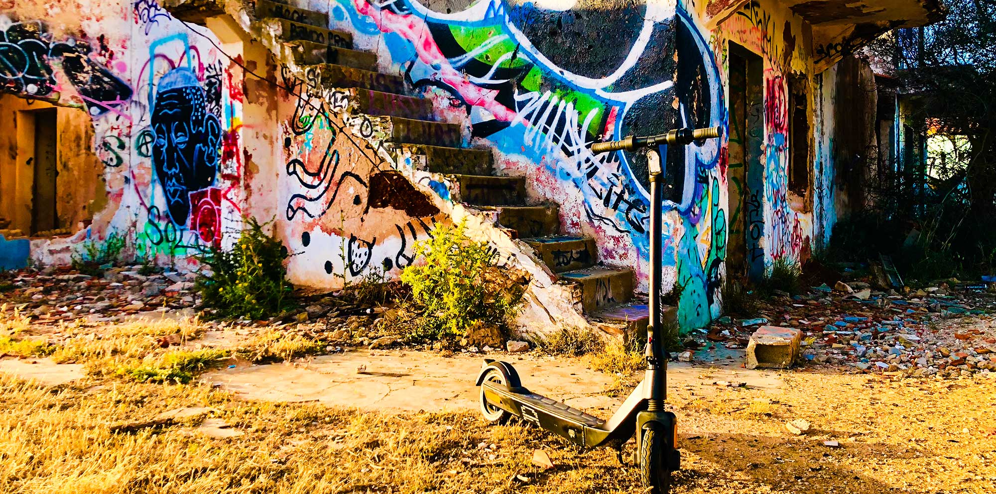 Shift iQ E-Scooter vor einem mit Graffiti besprühtem, verlassenen Haus.